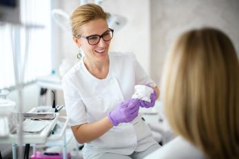 Zahnärztin erklärt Patientin Behandlung anhand eines Zahnmodells